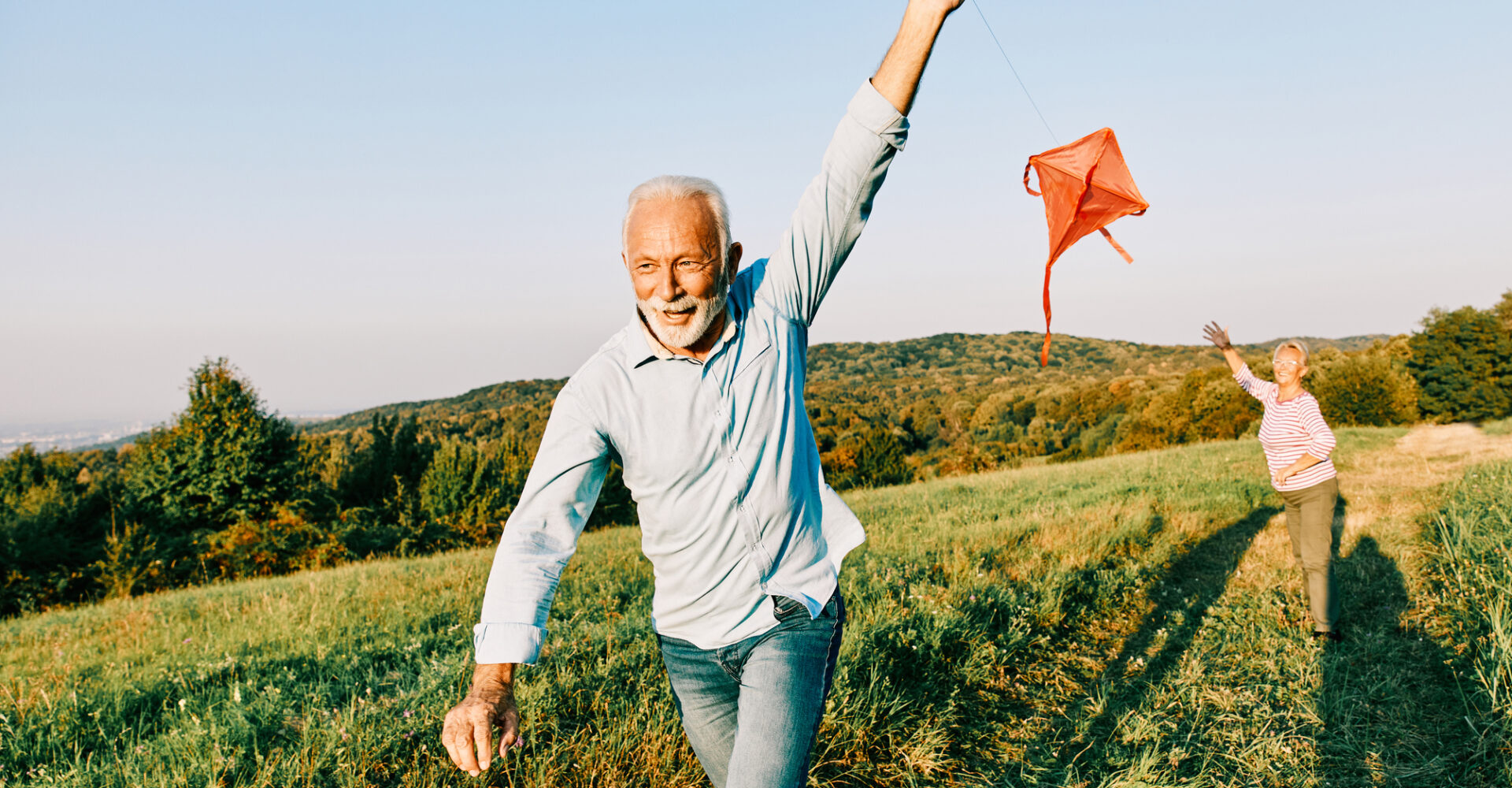 Senior couple flying a kite in a field.