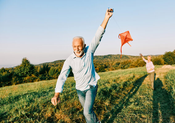 Senior couple flying a kite in a field.