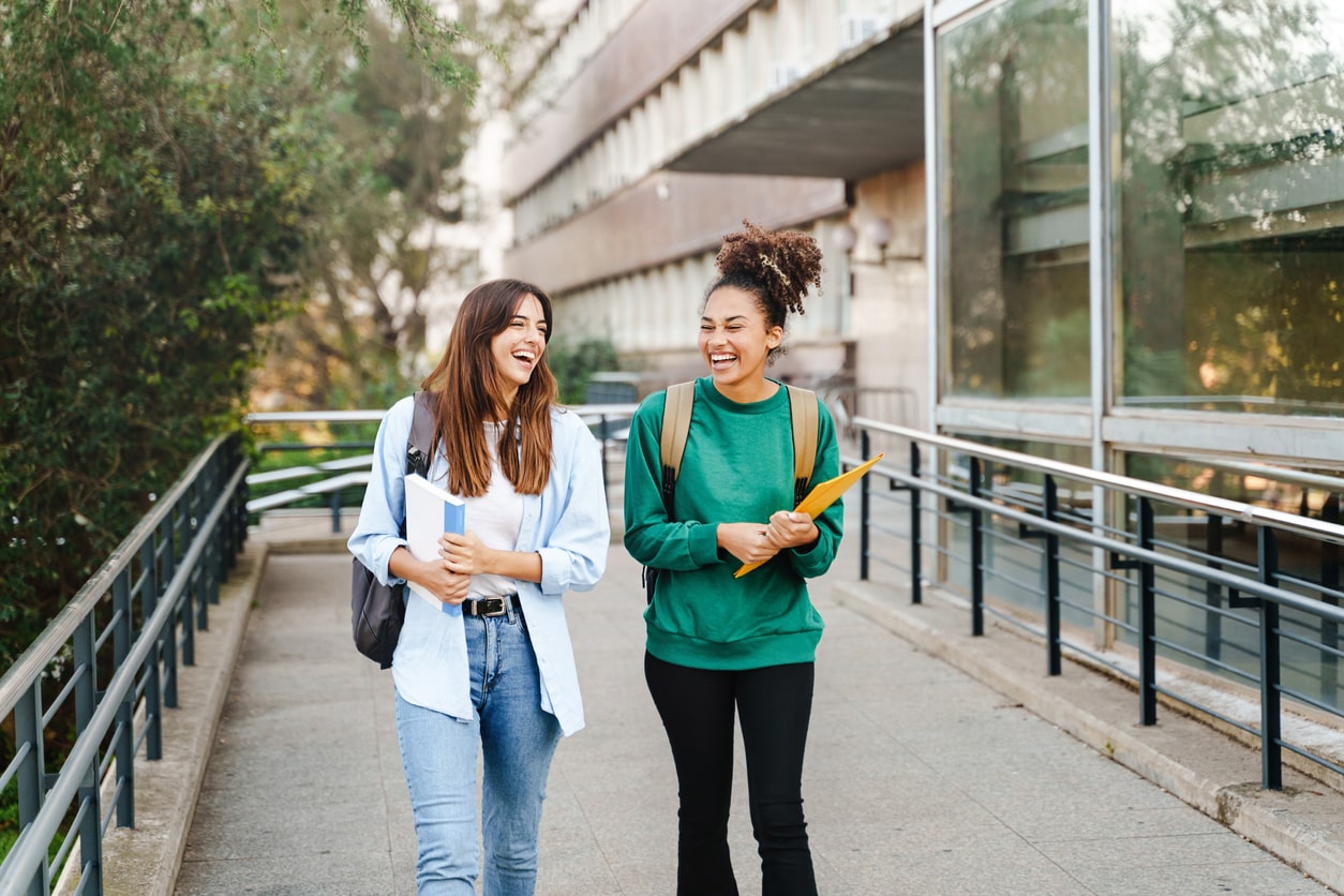 Two female students laughing and walking